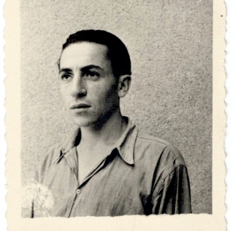 Photo en noir et blanc de forme carrée avec une bordure de polaroid d'un jeune homme regardant vers la gauche de la caméra. Ses cheveux sont coiffés vers l'arrière et il porte une chemise à col.